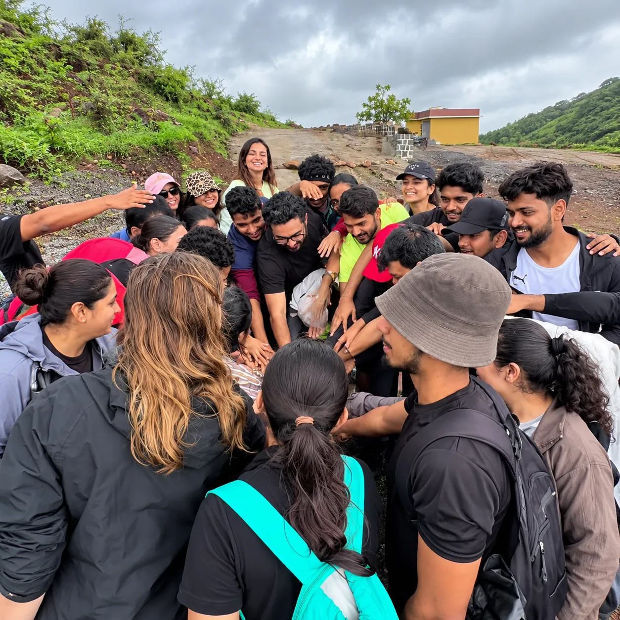 Trekking group in a team huddle on a green hillside